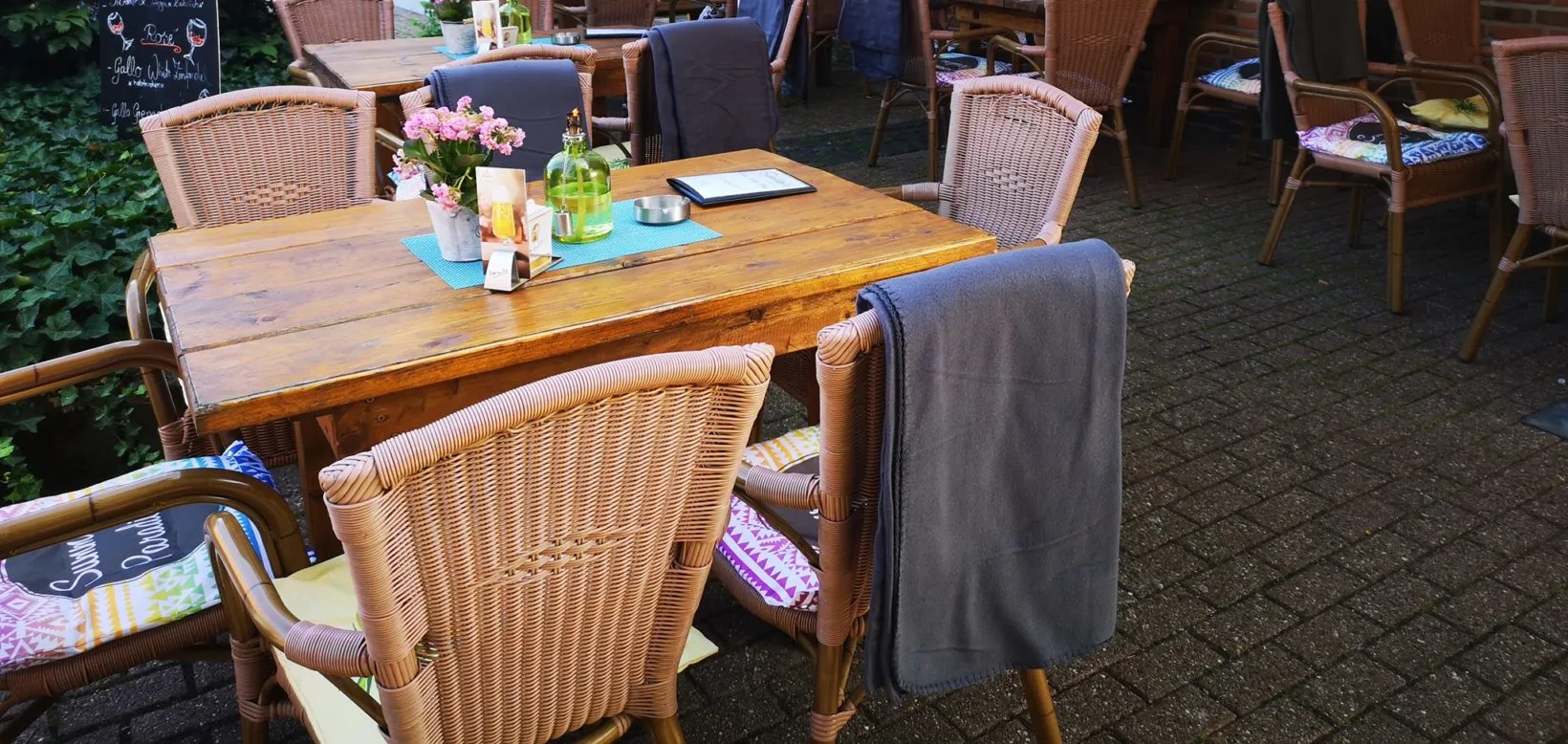 Terrasse des Bistro Schröders mit Rattan-Möbeln und Blumen